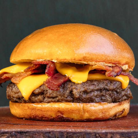 classic traditional burger meat cheese sun-dried beef on a neutral background on top of a wooden board